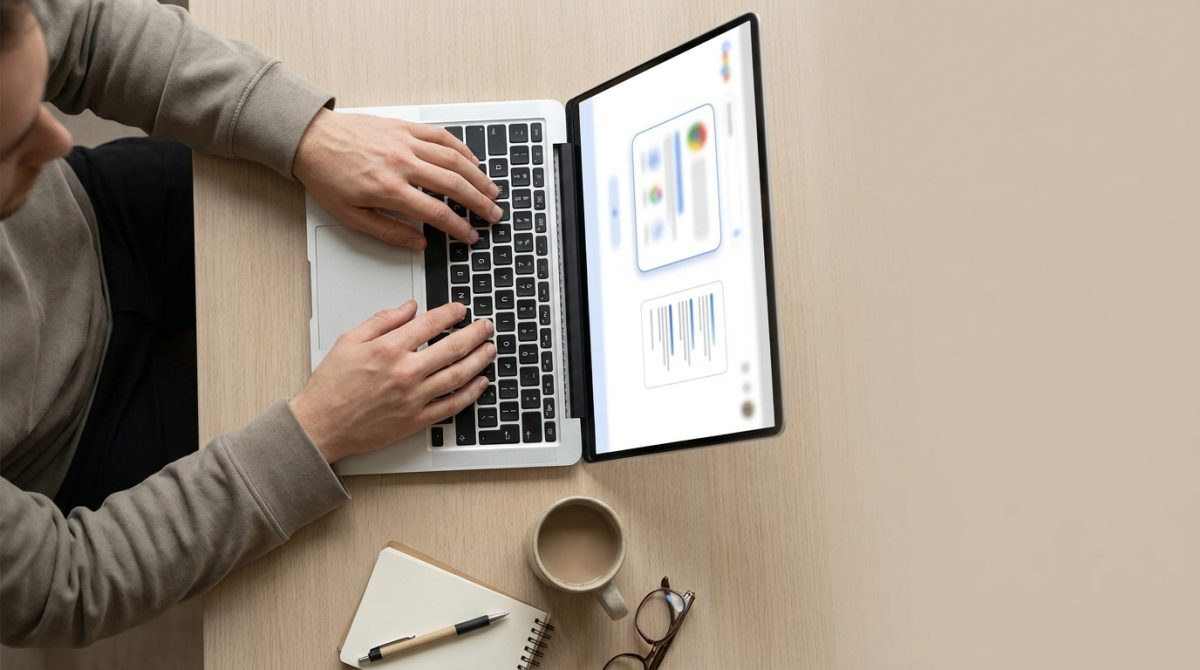 A person at a desk looking at a laptop showing a Google search results page with an AI Overview summary box at the top and organic results listed below it