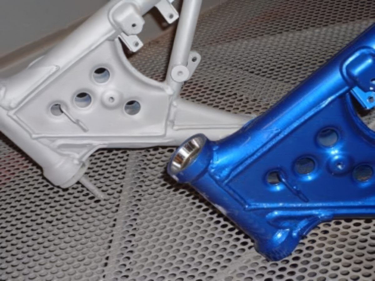 Two motorcycle frames after grit blasting, one white and one blue